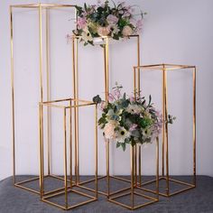 three gold geometric vases with flowers in them