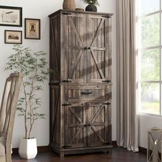 a tall wooden cabinet sitting in a living room next to a chair and potted plant