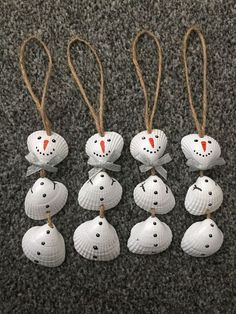 eight white ceramic ornaments with red noses and eyes on them are hanging from twine cords