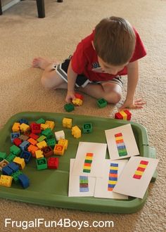 a young boy playing with legos on the floor in front of a green tray