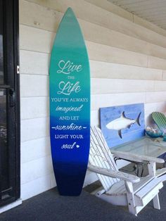 a surfboard sitting on the side of a building next to a table and chairs