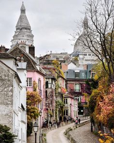 an old city street with buildings on both sides and a steeple in the background