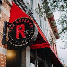 the sign is hanging on the side of the building that has red awnings