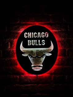 the chicago bulls logo is lit up on a brick wall in front of a red light