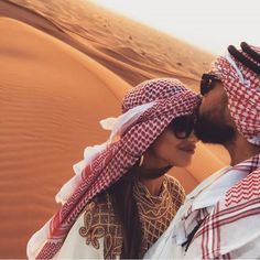 a man and woman are standing in the desert with their heads wrapped around each other