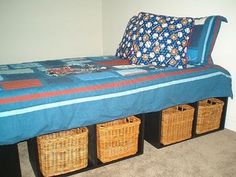 a bed with baskets underneath it and a blue bedspread on the bottom shelf