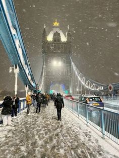 people walking across a bridge in the snow with cars driving on it and traffic passing by