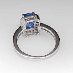 This gorgeous no heat blue sapphire ring is centered with a 1.64 carat cushion cut sapphire set into a four-prong head and is bordered with eighteen (18), bead set, round brilliant cut diamonds. The top face of the shank is accented with a row of seven (7), bead set, round brilliant cut diamonds on each side. The ring measures 10.2mm at the top, rises 6.4mm above the finger, tapering to 1.7mm wide and 1.1mm thick at the base of the shank. The ring is currently a size 4.75 and we offer complimentary resizing to fit. Formal Cushion Cut Lab-created Sapphire Ring, Blue Radiant Cut Lab-created Sapphire Ring, Radiant Cut Sapphire Ring In Fine Jewelry Style, Radiant Cut Sapphire Ring Fine Jewelry, Formal Radiant Cut Lab-created Sapphire Rings, Fine Jewelry Sapphire Ring Radiant Cut, Blue Tanzanite Rings In Radiant Cut, Cushion Cut Lab-created Sapphire Promise Ring, Cushion Cut Sapphire Promise Ring