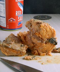 a knife and some food sitting on a table next to a can of red sauce