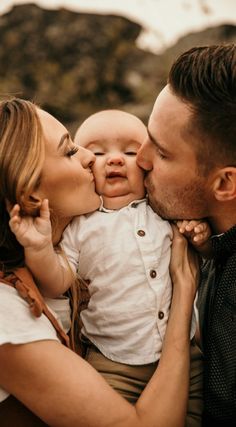 a man and woman kissing their baby while he is holding it up to his face