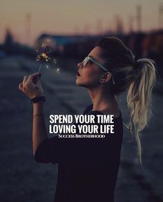 a woman holding a sparkler in her hand with the words spend your time loving your life