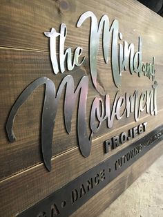 the sign for the mud and moved project is made out of wood, with metal lettering on it