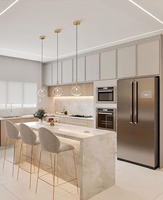 a modern kitchen with stainless steel appliances and marble counter tops, along with bar stools