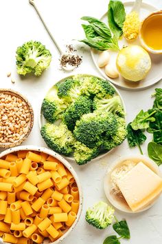 broccoli, pasta, cheese and other foods are arranged on a white surface