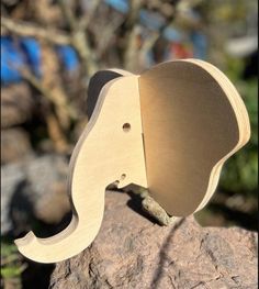 an elephant shaped wooden object sitting on top of a rock