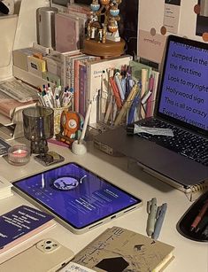 an open laptop computer sitting on top of a desk next to a pile of books