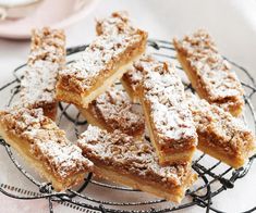 several pieces of pie sitting on a wire rack with powdered sugar toppings around it