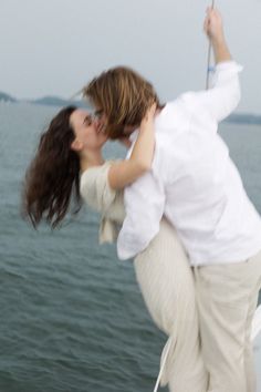 a man and woman kissing on the back of a boat