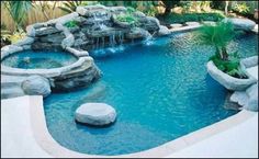 an outdoor swimming pool surrounded by rocks and plants