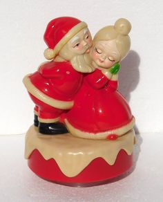 a ceramic figurine of santa and mrs claus hugging