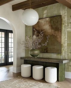 a large painting hangs above a console table with stools in the foreground and an area rug on the floor