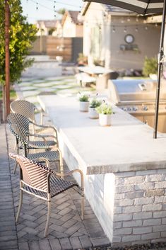 there are many chairs and tables outside on the brick patio with an umbrella over them