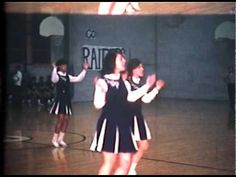 two girls in cheerleader uniforms on a basketball court with one girl holding a basketball