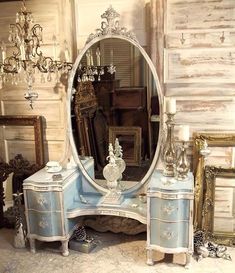 an ornate blue vanity with a mirror and chandelier in the background, surrounded by antique furniture