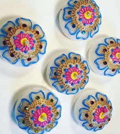 four blue and yellow flower shaped glass knobs on a white counter top with beads in the center