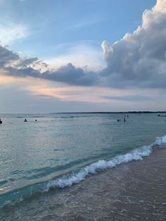 people are swimming in the ocean at sunset