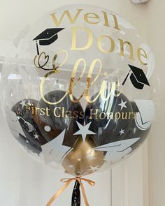 a clear balloon with gold foil lettering and graduation caps on it that says, well done & class hour