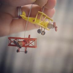 a tiny toy airplane is being held by someone's hand with the string attached to it