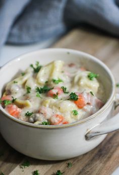 a close up of a bowl of food on a cutting board with parsley in the background