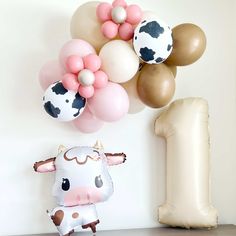 a cow standing next to some balloons in the air