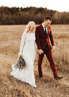 a bride and groom walking through a field