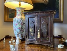 a vase sitting on top of a table next to a lamp and figurines