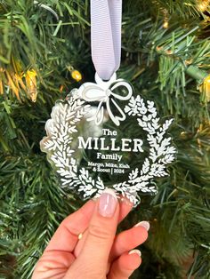 the miller family ornament hanging on a christmas tree in front of a woman's hand