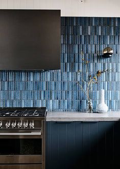 a stove top oven sitting inside of a kitchen next to a wall covered in blue tiles