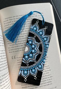 an open book with a tassel on top of it next to a blue and black bookmark