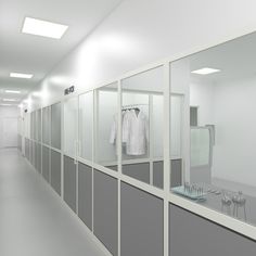 an empty hallway with glass partitions and clothes on hangers in the middle,