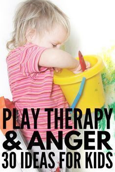 a toddler playing with a bucket and paint on the wall in front of it