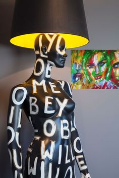 a lamp that is sitting next to a black mannequin with letters on it