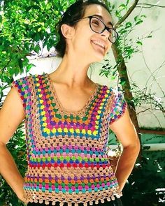 a woman wearing glasses and a crochet top standing in front of a tree