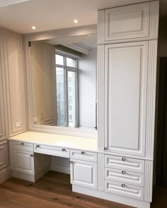 an empty dressing room with white cabinets and drawers