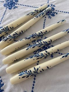 six blue and white ceramic utensils are lined up on a floral tablecloth