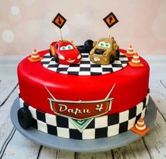 a red cake with cars on it sitting on top of a table