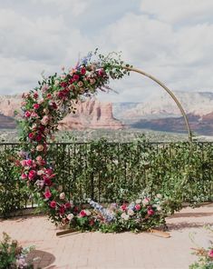 a wedding arch decorated with flowers and greenery in front of a scenic view at sedona lodge