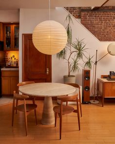 a table and chairs in a room next to a brick wall with lights hanging from it