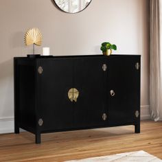 a black sideboard with gold accents and a round mirror on the wall above it