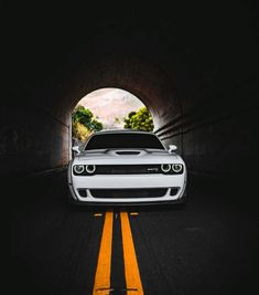 a white car is driving through a tunnel